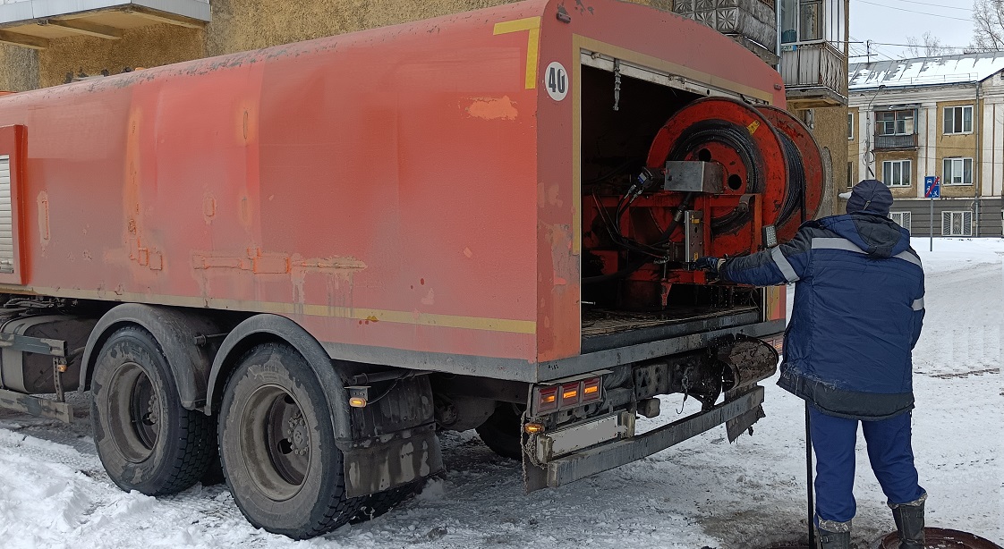 Каналопромывочная машина и работник прочищают засор в канализационной системе в Городище